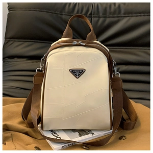 Detail of beige PU leather backpack with irregular stitching and metallic logo on sofa