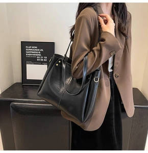 Vista laterale di una grande borsa tote in pelle nera con rivetti dorati indossata