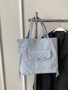 Sac fourre-tout bleu clair avec texture plissée et nœud sur un cintre minimaliste