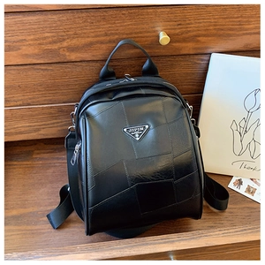Detail of black faux leather backpack featuring geometric patchwork and silver metal logo
