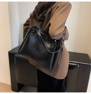 Dettaglio della grande borsa tote nera con trama vintage e rivetti dorati laterali