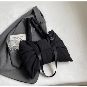 Détail du sac matelassé en nylon à nœud avec double bandoulière sur costume gris