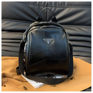 Detail of black patchwork faux leather backpack with silver triangular metal plaque