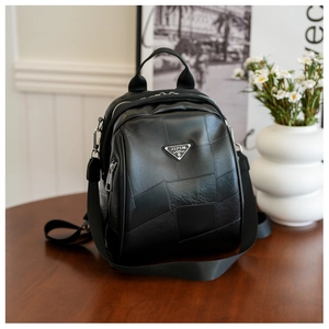 Detailed view of black patchwork leather backpack with geometric texture and metal logo