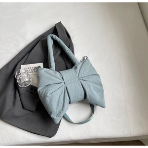 Détail du sac en nylon matelassé bleu clair avec un design de nœud bouffant et texture douce