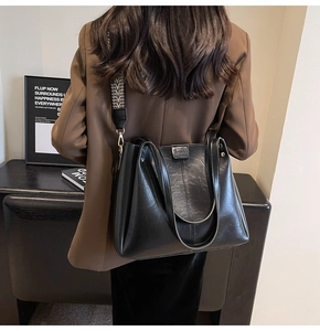 Dettaglio della borsa tote nera con un'ampia tracolla intrecciata in bianco e nero