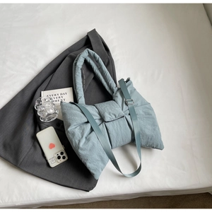 Détail d'un sac cabas matelassé bleu clair avec forme de nœud et texture rembourrée