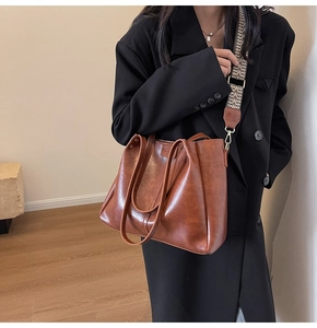 Dettaglio della borsa tote marrone vintage con tracolla decorativa in tessuto e trama in pelle