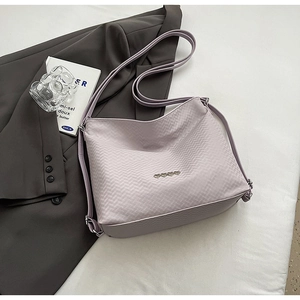 Close-up of light purple woven shoulder bag with metal heart details on grey blazer