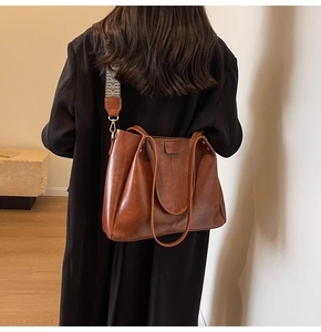 Vista posteriore dettagliata di una borsa tote vintage marrone con tracolla larga in tessuto