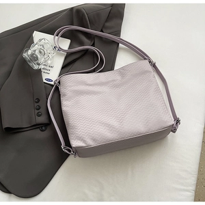 Close-up of lavender shoulder bag with herringbone texture and adjustable strap detail