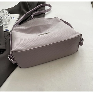 Detail of lavender textured crossbody bag featuring silver hardware and a logo plaque