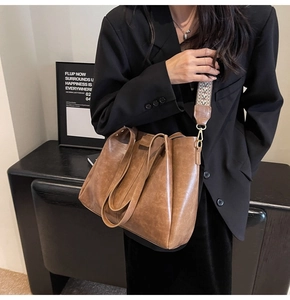 Dettaglio borsa tote in pelle cerata marrone con tracolla in tessuto e finiture in oro lucido