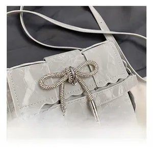 Close-up of textured leather crossbody bag featuring a sparkling rhinestone bow buckle