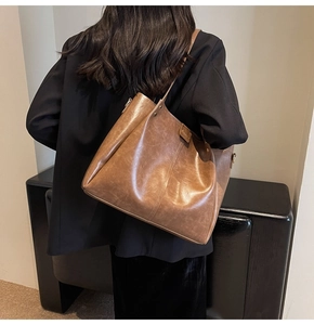 Dettaglio della borsa tote in pelle marrone vintage con tracolla larga indossata da una modella