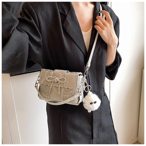 Detailed shot of gray woven bag with rhinestone bow and cute plush charm on blazer