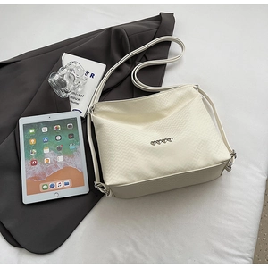 Detail of cream quilted leather bag with heart accents on grey suit background