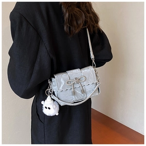 Detail of silver woven shoulder bag with wavy flap, metal bow and plush monster charm