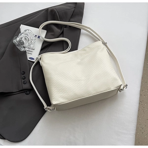 Detail of cream tote bag featuring textured chevron weaving and silver metal hardware