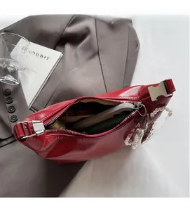 Détail du sac hobo en cuir verni rouge montrant l'intérieur spacieux et les finitions argent
