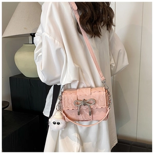 Pink woven crossbody bag with diamond bow and fur ball charm on white shirt