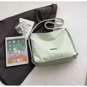 Detail of mint green crossbody bag with wave texture and heart-shaped metal accents