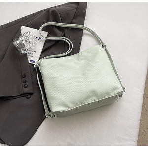 Detail view of the mint green woven crossbody bag with V-shaped texture and silver buckle