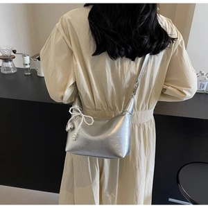 Détail du sac croissant argenté métallisé avec breloque nœud en perles élégante