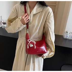 Gros plan sur le sac en cuir verni rouge avec nœud en perles et pendentif cœur de luxe
