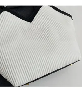 Detail of white pleated tote bag with black V-shaped trim and gold fashion lettering
