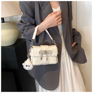Detail of cream white woven bag with ruffled edges and rhinestone bow and plush lamb