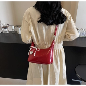 Détail du sac rouge en cuir avec nœud en perles décoratif et breloque en forme de cœur