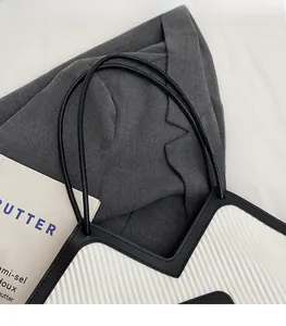 Detail of accordion pleated fabric tote with black leather trim and thin straps