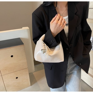 Détail du sac à main en cuir verni blanc crème avec lanière perle et pendentif cœur argent