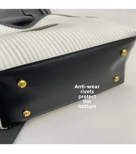 Detail of anti-wear golden rivets on the bottom of black and white tote bag