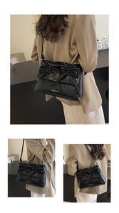 Detail of black pleated shoulder bag featuring elegant bow accents and metal logo