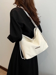 Minimalist beige woven tote bag with silver heart studs shown in a lifestyle shot