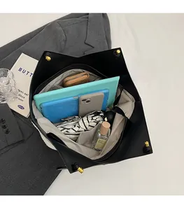 Top view of spacious interior of black tote bag showing gadgets, umbrella and tablet