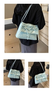 Detail of light blue crossbody bag with ribbon bows and wrinkled leather texture