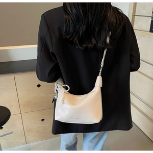 Détail du sac demi-lune en cuir blanc cassé avec élégante breloque perle et bandoulière