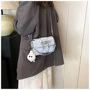 Detail of light blue crossbody bag with metallic wrinkled texture and diamond bow charm