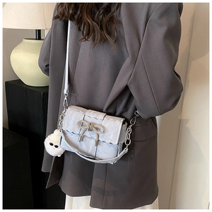 Light blue crossbody bag with wave edges, diamond bow, and fluffy charm shown on model