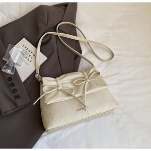 Detailed view of beige ballet-style bag with bow accents and pleated leather texture