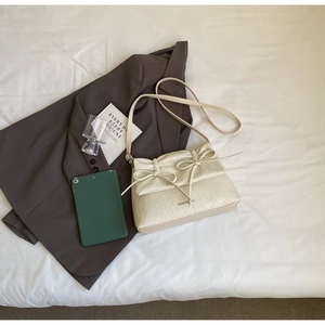 Close-up of beige ballet style shoulder bag with pleated texture and bow detail