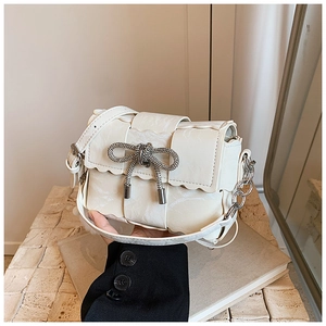Detail of cream white leather bag featuring a wave flap and sparkling silver bow