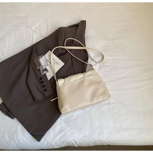 Detail of beige pleated faux leather crossbody bag with minimalist shoulder strap detail