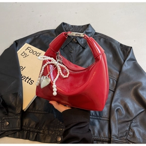 Détail du sac hobo rouge brillant avec nœud en perles, pendentif cœur et boucle