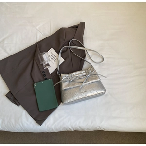 Close-up of silver ballet-style shoulder bag with metallic crinkle texture and bow detail