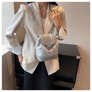 Dettaglio dello zaino a secchiello grigio ricamato con texture floreale e catene su modella