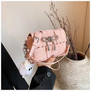 Close-up of pink ruched crossbody bag with crystal bow detail and fluffy pendant charm